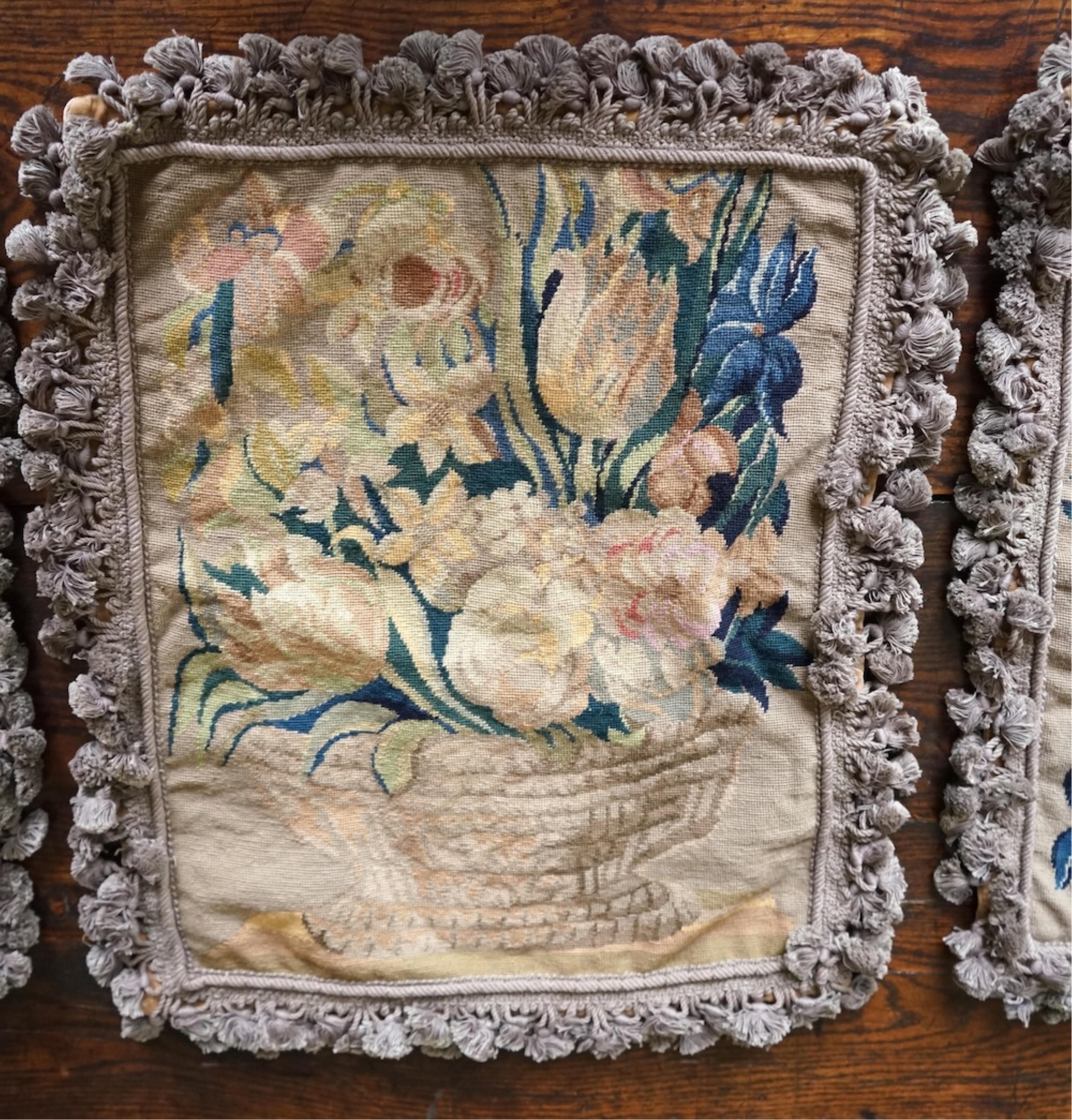 Four large rectangular wool worked cushion covers, with a still life design of a bowl of roses, tulips and daffodils. Embroidered in very muted colours, with ornate tasseled braid and velvet backing. 48cm high x 39cm wid